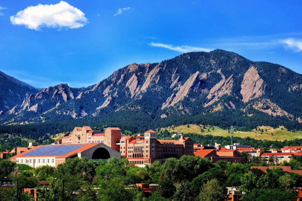 Flatirons rising above red-roofed buildings in Boulder County, CO