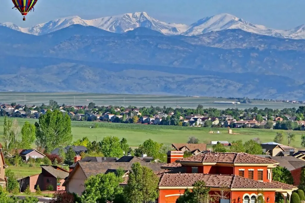 Hot air balloon over homes in Erie, CO with snow-capped mountains