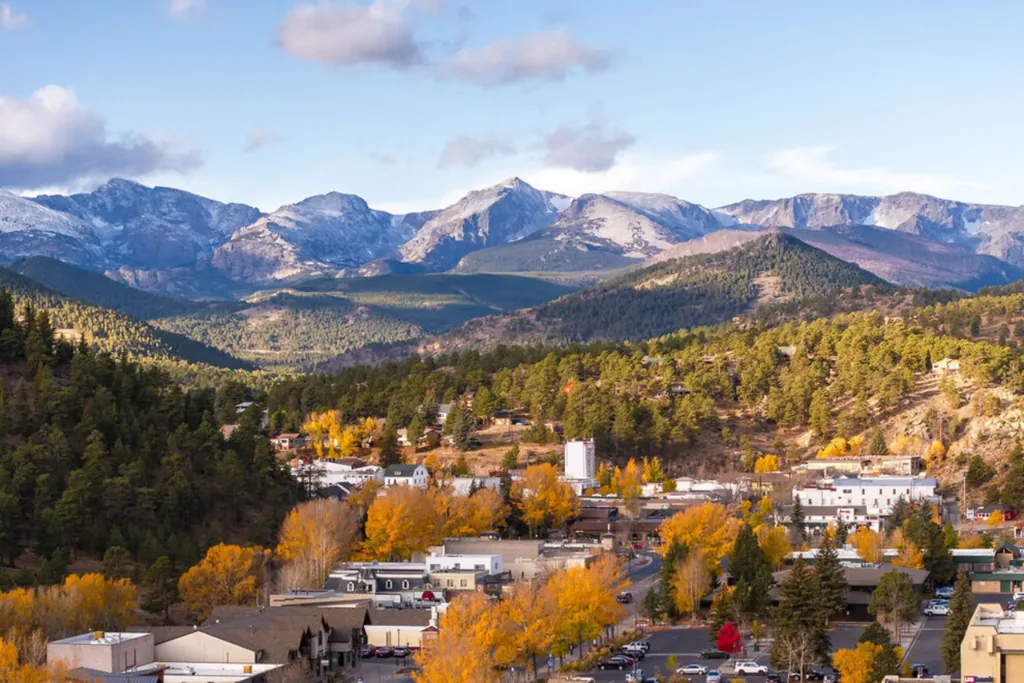 Estes Park, CO town below snow-capped mountains in autumn