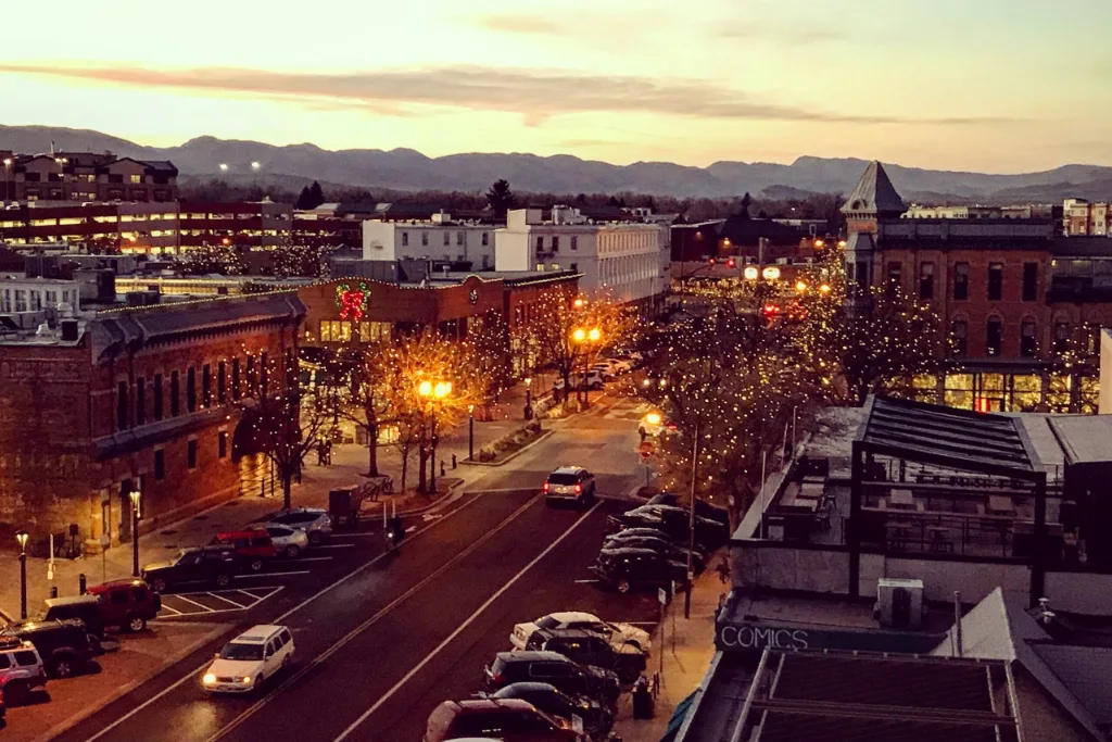 Downtown Fort Collins, CO street lit at dusk with mountains on the horizon